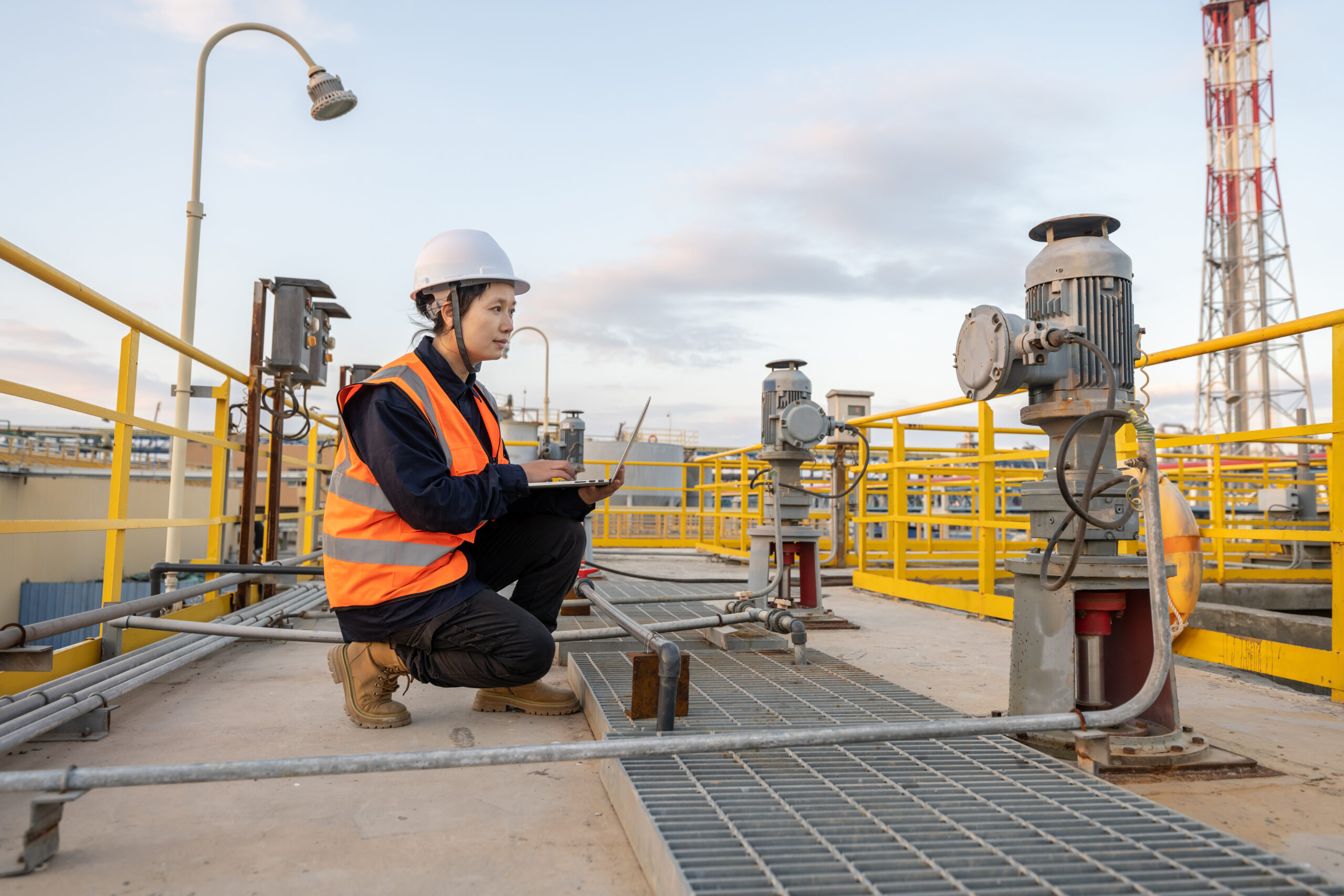 A female engineer works in a chemical plant using a laptop computer